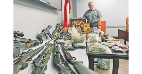 Deputies and drug agents confiscated numerous firearms, a reported three pounds of marijuana, and a stash of cash from a Pecks Road residence last week.