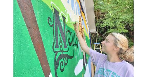 Whitney Little works diligently on the new mural that now decorates the side of The Nugget office.