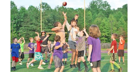 With a camper on his back, LCHS Football player Walker Scott looks to provide an assist to the group of first and second graders on his team during the LCHS Youth Football Camp last week.