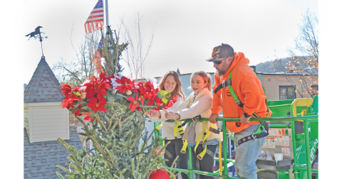 Skyler Alexander (left) and Ariel Alexander from City Hall and Jeremy Tanner from the City Works Department attach the wreath on the Christmas tree on the square.