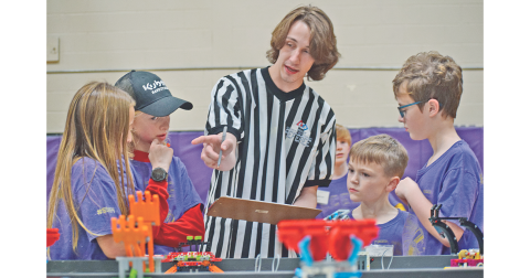 Members of the Bright Chickens of Lumpkin County Elementary School, from left, Chloe Fulton, Liam Alhadeff, Jacob Gee and Jacob Giles gather around First LEGO League referee Liam Orton as he explains the scoring process at Saturday’s competition.