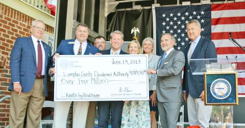 Officials hold up a check representing over four million dollars in state grant funding for broadband internet expansion in Lumpkin County. Pictured (from left) are Development Authority Board Chairman Henry Davis, Representative Will Wade, Board of Commissioners Chairman Chris Dockery, Governor Brian Kemp, First Lady Marty Kemp, Development Authority Director Rebecca Mincey, Windstream CEO Tony Thomas and Senator Steve Gooch.