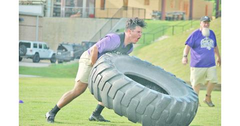 Trenton Brooksher powers a tire over during the relay race as Coach Stoney Lunsford looks on.