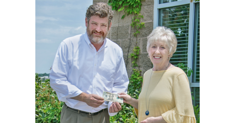 Cornelia resident Donna Shirley receives her $100 prize money from Alan NeSmith, Community Newspapers Inc. chairman. Shirley’s photograph of the double waterfalls that make up Anna Ruby Falls graces the cover of the 2023 summer edition of The Mountain Traveler magazine. (Photo/Kimberly Brown)