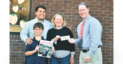 Jonathon, Sarah, and Jonathon Barge Jr., who goes by “J,” are all smiles having learned that Jonathon Barge won the Winter 2022 Lake Living cover contest for the picture of “J” in the family’s 1972 Alumacraft fishing boat “catching snowflakes instead of fish” on Lake Burton in January 2022. Enoch Autry, publisher of The Clayton Tribune in Rabun County, right, hands the family the $100 prize for winning the contest. (Photo by Megan Broome)