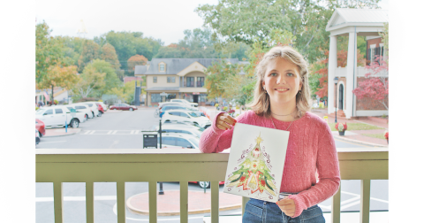 Home school student Amelia Taylor shows off her winning Christmas T-shirt design on the balcony of the Visitors Center in downtown Dahlonega.