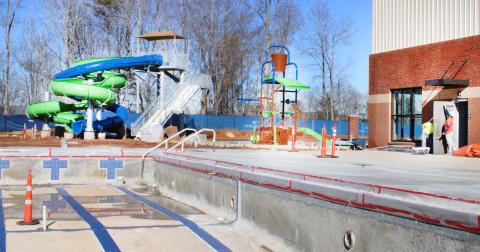 Crews with Carroll Daniel Construction do some finishing work at the rear of the main building. A fully-automated pump house on the opposite side of the competition pool will treat and distribute the swimming water for the entire facility.
