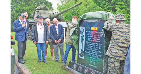 Veterans Hal Williams (left) and Chuck Windham peel back a camouflage covering to reveal the new Vietnam Memorial monument.