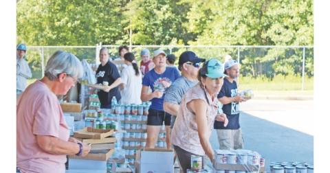 Volunteers organize cans of food and prepare to load them into waiting vehicles at the Unseen Hand Ministry mobile pantry at the parking lot of Blackburn Elementary School in Dahlonega.