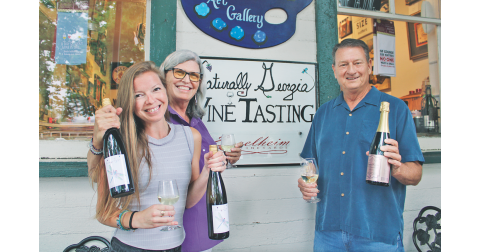 Naturally Georgia manager Amanda Holt (left) and owner Vickie Cooper show off bottles of their proprietary Dragonfly White, while Engelheim Vineyards owner Gary Engel displays his new sparkling Glitzern.