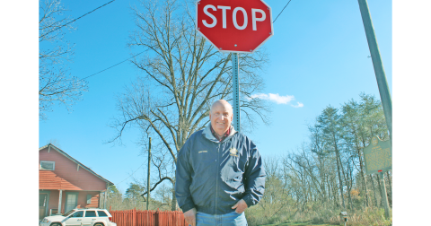 Lumpkin County Special Projects Manager Charles Trammell stands at the intersection of Castleberry Bridge Rd. and Auraria Rd., next to one of 11 flashing stop signs in the county.