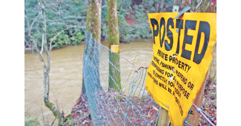 “No trespassing” signs delineate private property near the Etowah River bridge on Ga. Hwy. 52, a popular put-in spot for local floaters and paddlers. The Etowah is not technically considered navigable, so its waters could be restricted if the property on both sides is marked private.