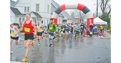 Eventual race winner Matt Bird (left) leads the pack away from the starting line of the Wimpy Mile on Saturday morning.  Despite a cold, steady rain, participants showed up in impressive numbers for the fourth-annual charity event. (Photo by John Bynum)