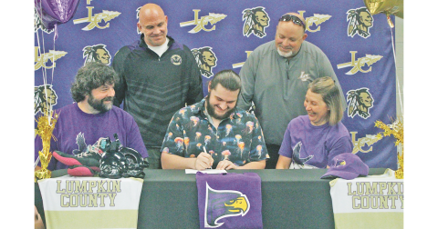Hayden Roy is set to continue his wrestling career at Hunter College in New York City. Pictured: Roy signs his official commitment surrounded by his parents and coaches.