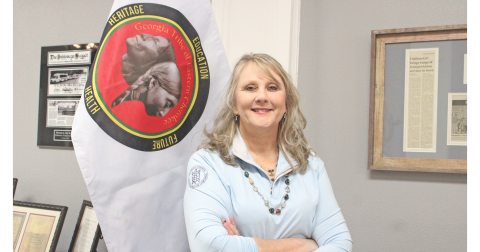Rhonda Bennett, Council Chair of the Georgia Tribe of Eastern Cherokee, stands next to a flag representing her tribe.
