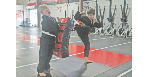 Zeke Perkins holds his ground as Aiden Hawkins practices a thunderous kick during Hapkido practice.