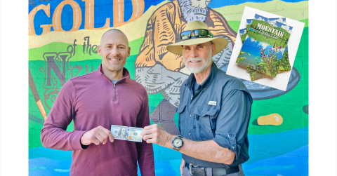 The Dahlonega Nugget Publisher John Bynum (left) presents the $100 prize to local resident Bill Perdue for his winning photo. Perdue captured the photo for the cover of the summer edition of The Mountain Traveler magazine.