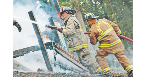 Lumpkin County firefighters Paul Northop, left, and Jean-Luc Cypher work to contain a quickly-spreading fire that ultimately claimed a Trahlyta Estates home last Friday.