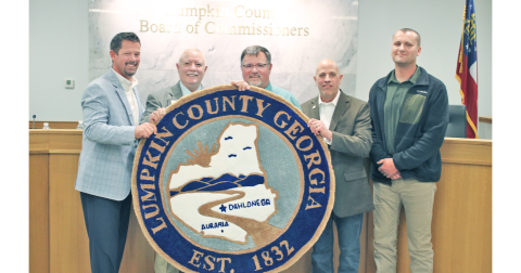 Chairman Chris Dockery (center) holds up a custom rug modeled after the Lumpkin County seal during his final meeting with the Board of Commissioners. The rug was a parting gift from fellow commissioners (from left) Tucker Greene, Dr. Bobby Mayfield, Jeff Moran and Rhett Stringer.
