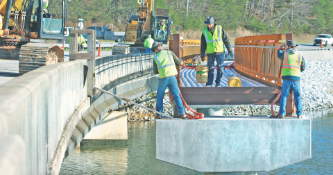 City contractors work to install segments of the much-anticipated pedestrian bridge at Lake Zwerner.