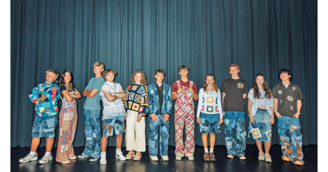 Junior Jeb Jackson (center) is flanked by 10 student models wearing his clothing brand, One Fifty Three Designs, during a charity fashion show held last month in the high school auditorium.