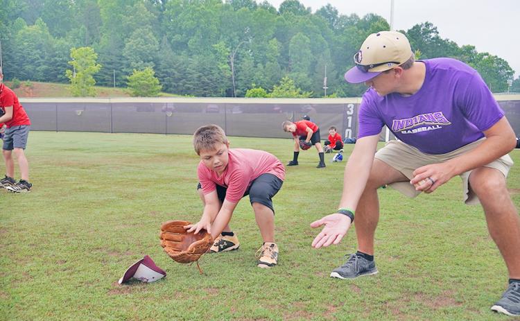 LCHS alum and LCMS Baseball Coach Daniel McCrary (right) shows Kason Dehne the proper ready position as an infielder preparing to field the ball during the Lil’ Indians Baseball Camp held at the high school last week.