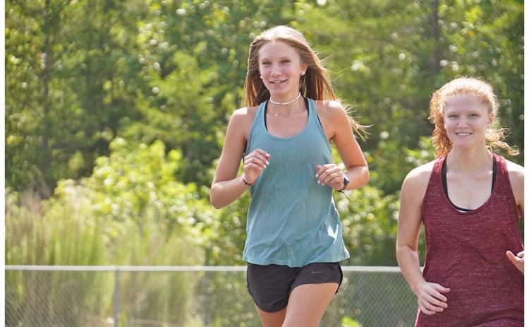 Abbie Hilchie (left) and Kelly Cronan, get warmed up during a recent practice. Hilchie led the way for the girls during their first meet on Thursday, taking fifth overall with a time of 23:15 to help push her team to fourth place at the meet.