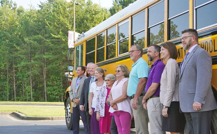 Members of the Board of Education and Central Office staff pose for a photo with one of the system's new buses.