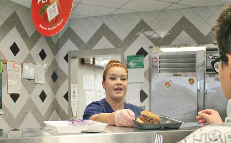 School nutrition specialist Sarah Vincze prepares a barbecue sandwich for a student at Lumpkin County High School.
