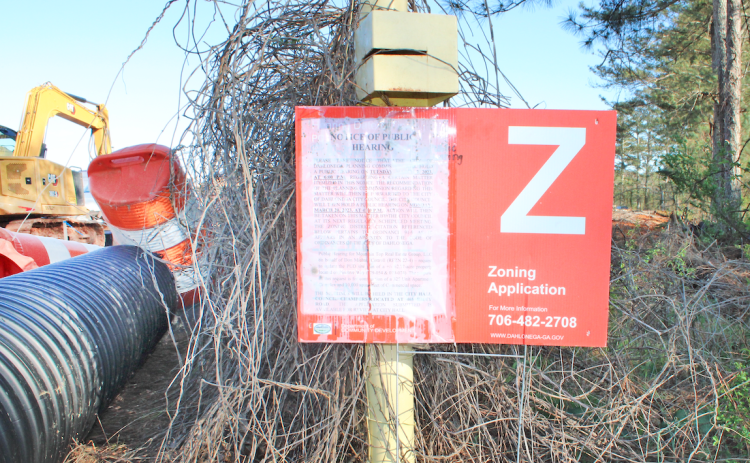 A sign advertising the March 7 meeting of the City Planning Commission stands at the end of Pinetree Way. Residents showed up to the hearing to express their skepticism of the project, which would include a 325-unit apartment complex and 10,000 feet of commercial space.