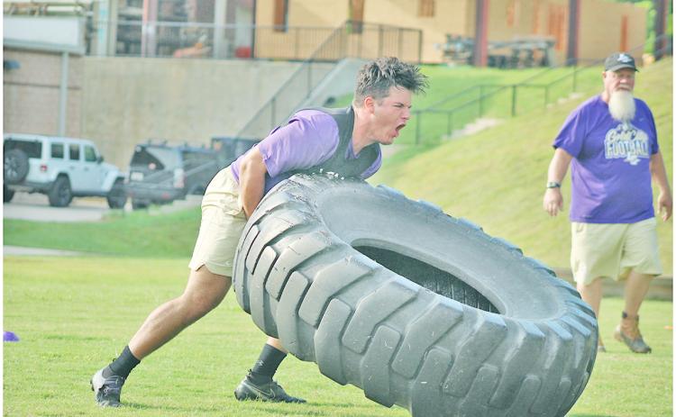 Trenton Brooksher powers a tire over during the relay race as Coach Stoney Lunsford looks on.