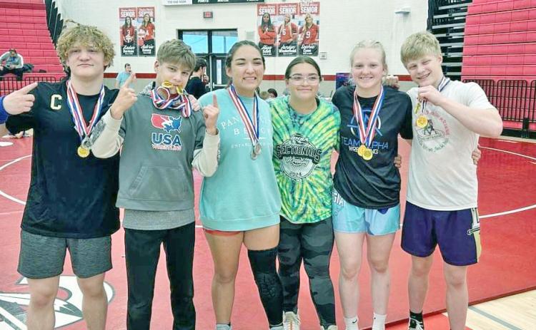 Lumpkin wrestlers Nathan Nielsen, Liam Nielsen, Maddie Mendoza, Nattalie Mendoza, Greta Garbuzovas and Xander Nielsen share a moment at the Warrior Invitational.