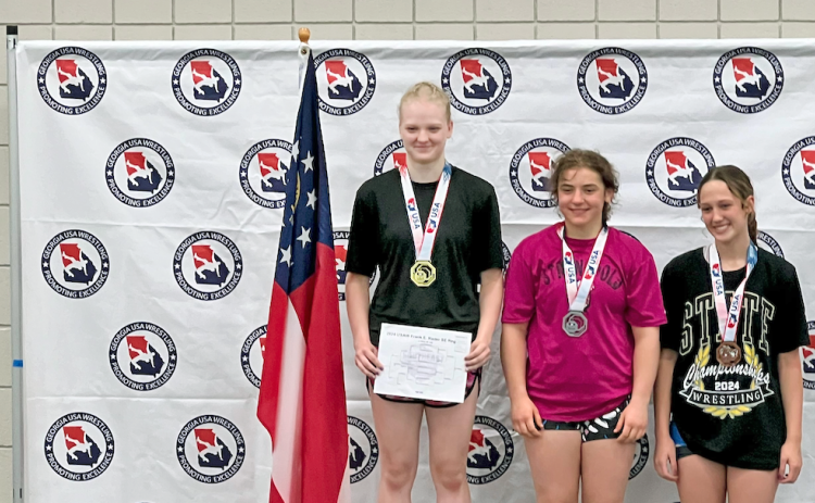 Greta Garbuzovas (left) stands atop the podium at the Southeast Regional Championships.