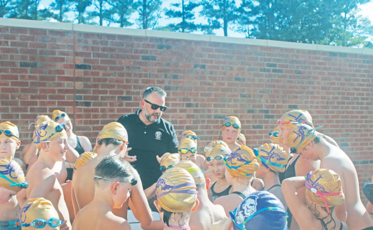 Lumpkin County Coach Jesse Turk leads the young swimmers in a chant before the team dove into the competition.