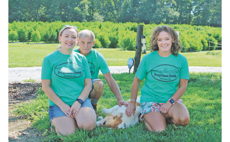Pictured, from left, Lacey White, Bruce White, Barney the dog and Kelly White enjoy a shady patch of grass on the White Family Barn Farm.