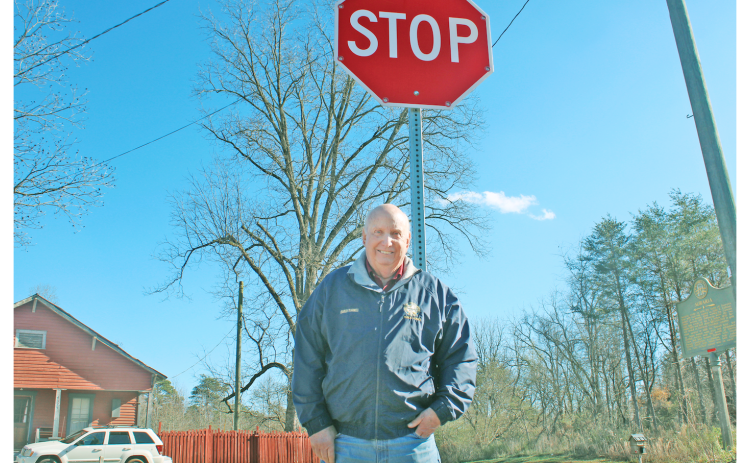Lumpkin County Special Projects Manager Charles Trammell stands at the intersection of Castleberry Bridge Rd. and Auraria Rd., next to one of 11 flashing stop signs in the county.