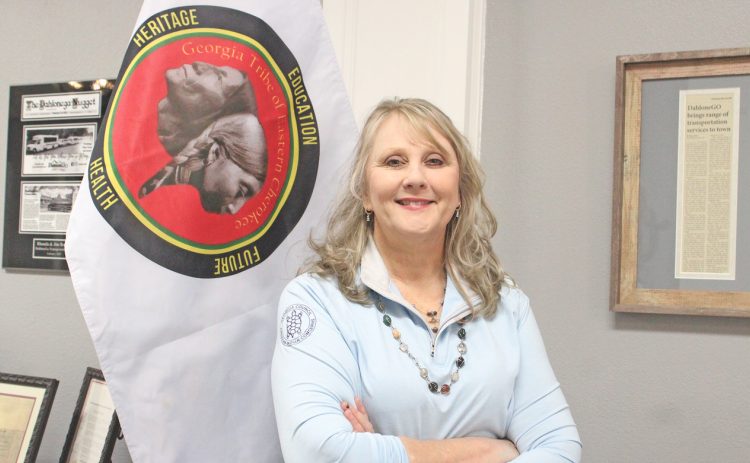 Rhonda Bennett, Council Chair of the Georgia Tribe of Eastern Cherokee, stands next to a flag representing her tribe.