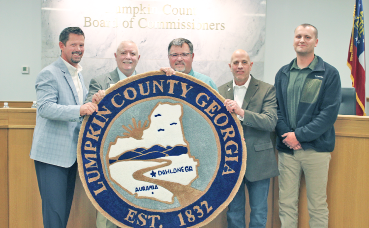Chairman Chris Dockery (center) holds up a custom rug modeled after the Lumpkin County seal during his final meeting with the Board of Commissioners. The rug was a parting gift from fellow commissioners (from left) Tucker Greene, Dr. Bobby Mayfield, Jeff Moran and Rhett Stringer.