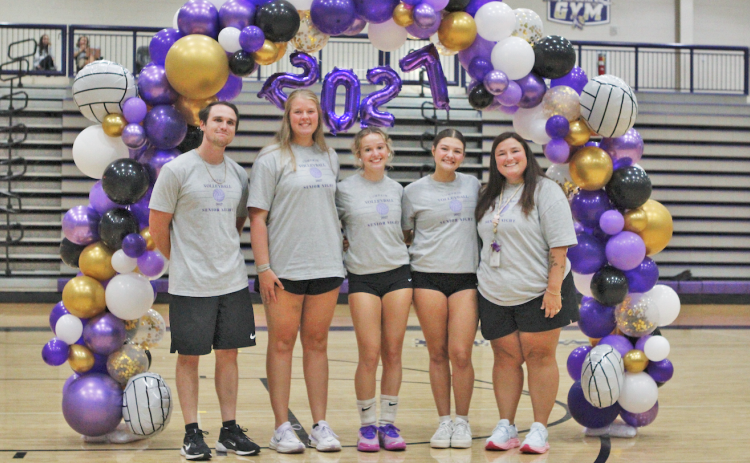 Senior players Lena Timmons (center) and Marley Rodriguez (center right) celebrate Senior Night surrounded by their coaches.