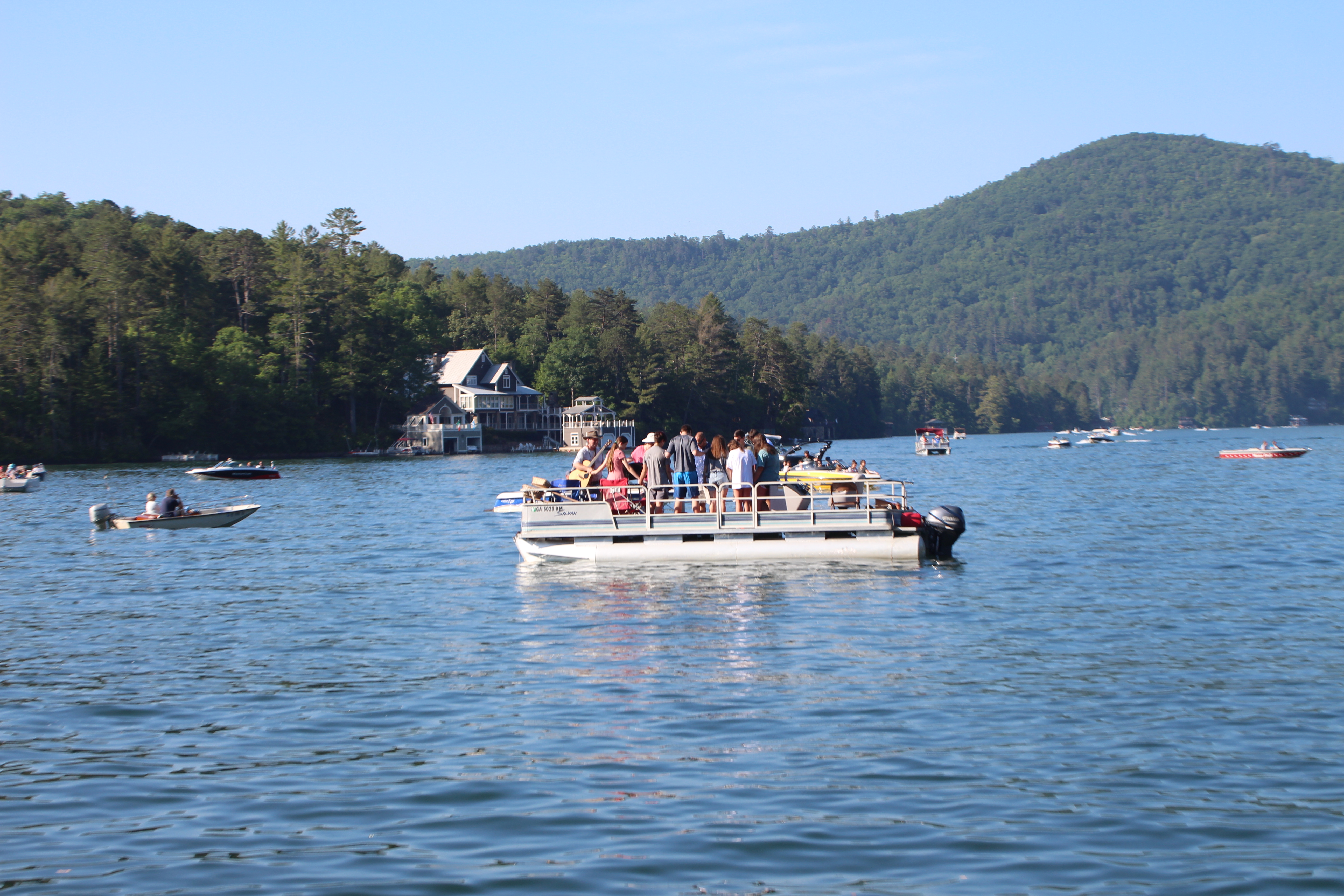 The Rev. Zack Martin and the Rev. Jeremy Noffsinger pray with the youth group on a pontoon boat at Lake Rabun for boat church at Clayton First United Methodist Church. (Photo/Megan Broome)