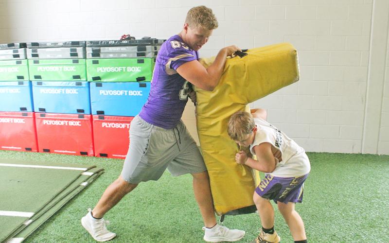 LCHS football player Aaron Hopkins teaches a camper the proper way to drive an opponent backwards during a drill.