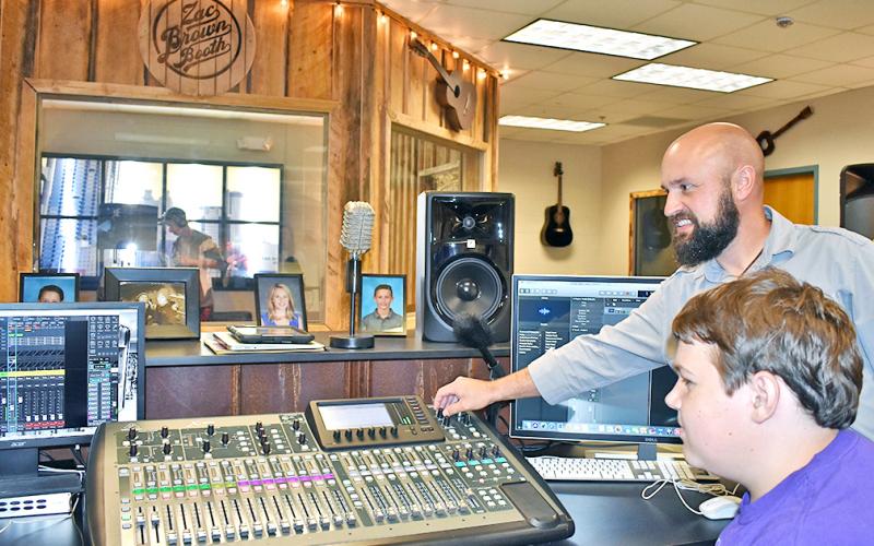 Music teacher Radford Windham shows student Brendan Diehl some of the many functions of a soundboard, purchased with money donated by Mike and Lynn Cottrell.