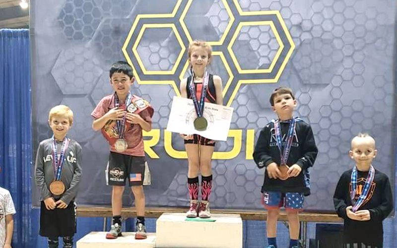 Allie Procter stands on top of the podium after winning her third straight Youth Georgia Wrestling State Championship title recently. Procter, 8, racked up three wins by pin versus her male opponents to secure her third straight championship title.