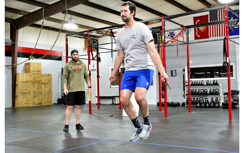 Jordan Meeks jumps rope during a workout at CrossFit Dahlonega as trainer and gym owner Thomas Coggins oversees the session.