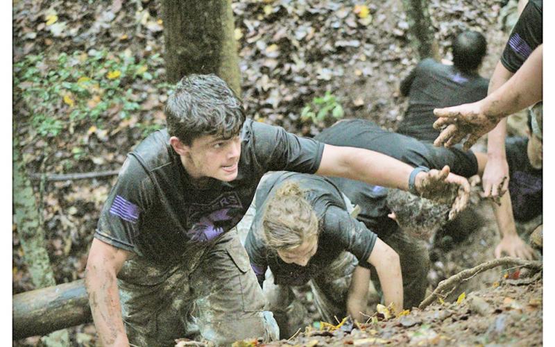 Chase Cootware reaches out for his teammate's hand as the team works together to cross a steep and slippery trench.