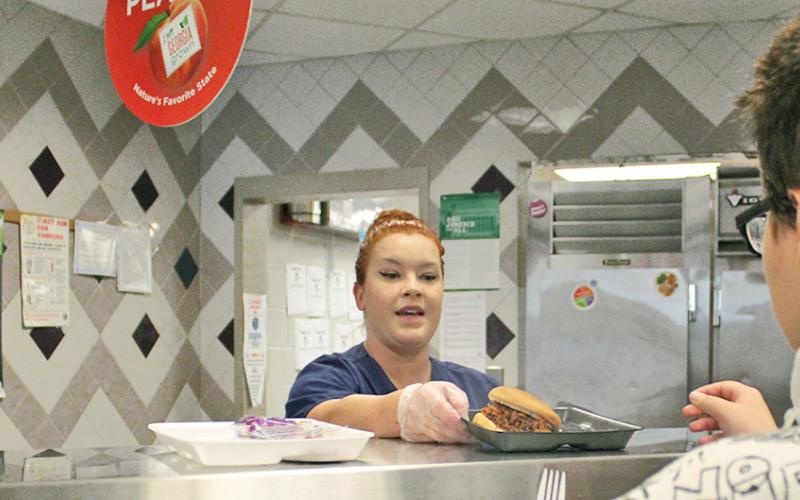 School nutrition specialist Sarah Vincze prepares a barbecue sandwich for a student at Lumpkin County High School.
