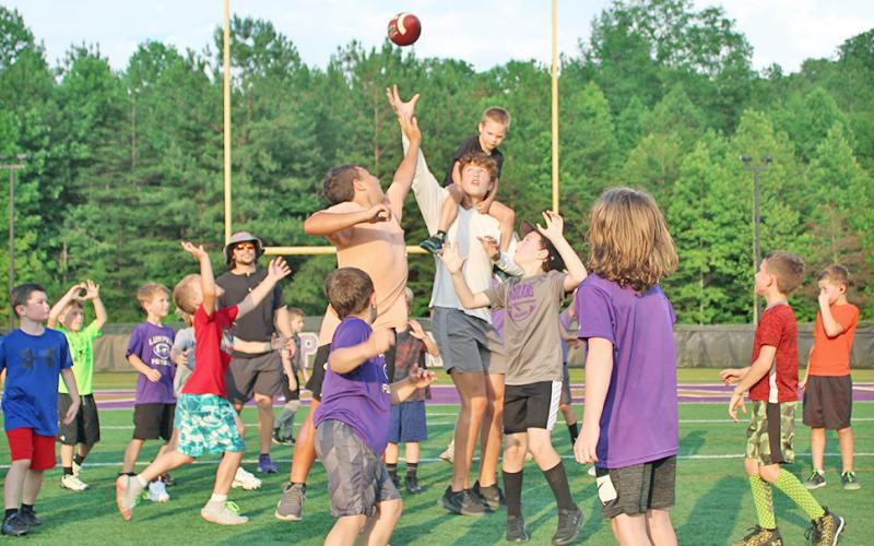With a camper on his back, LCHS Football player Walker Scott looks to provide an assist to the group of first and second graders on his team during the LCHS Youth Football Camp last week.