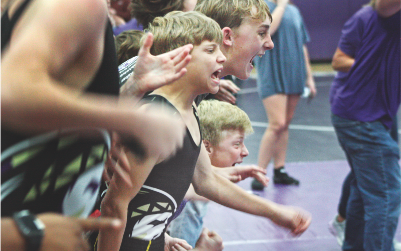 Middle school wrestlers Liam Nielson, Caleb Soles, and Alexander Nielson cheer on one of their teammates during the Lumpkin County match at Clear Creek last week.