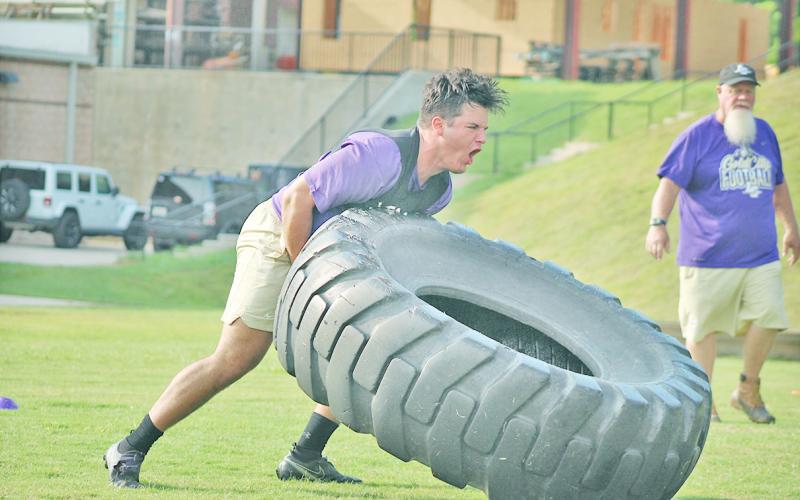 Trenton Brooksher powers a tire over during the relay race as Coach Stoney Lunsford looks on.