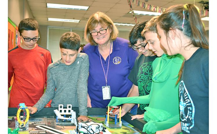 Lumpkin County’s School System Teacher of the Year, Tori Jones, oversees student members of an after-school group doing what Jones believes to be the key to education—hands-on learning. They are members of the Middle School’s FIRST LEGO League Team working (on Halloween) to build robots to accomplish a real-world task. From left are Jon Gooby, Samuel Fuerstenberg, Jones, Cameron Allison, Nathan Berzack and KayLeigh Zahn. The students will compete with other FIRST LEGO League teams Nov. 23—their first year t